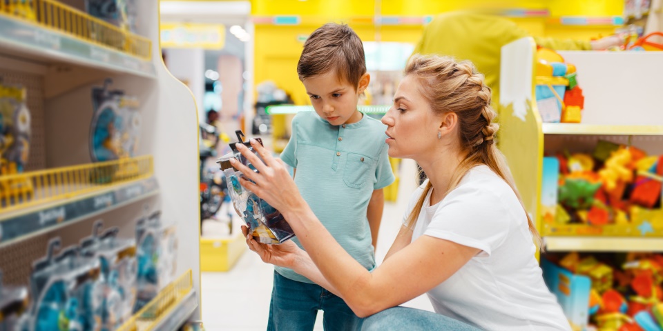 Das Foto zeigt eine Frau und einen Jungen, die Spielzeug in einem Geschäft anschauen.